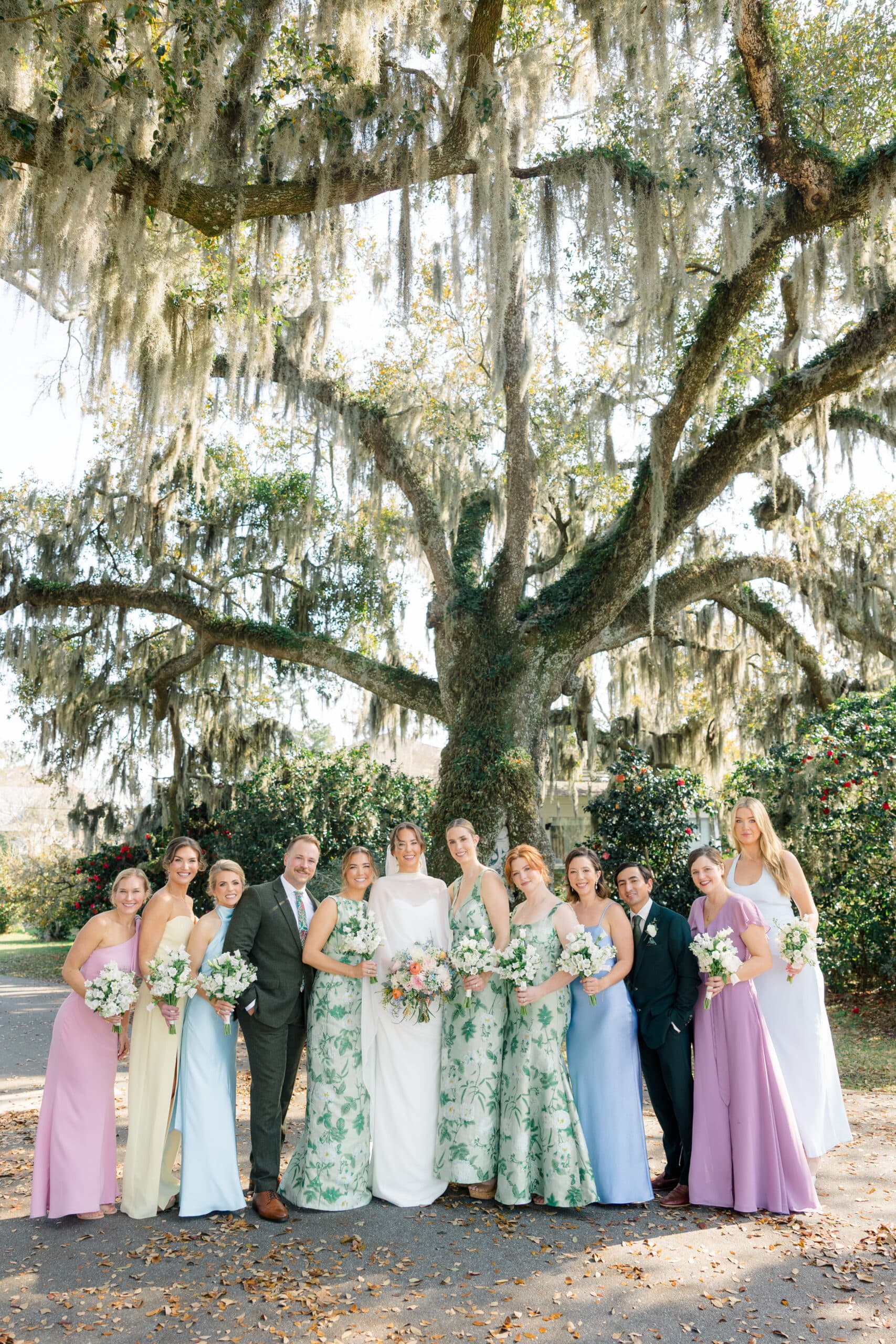 Bridal party in pastel gowns beneath an oak