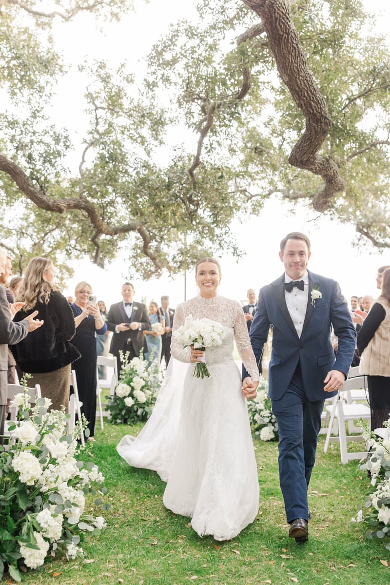 Newlyweds walking back down the outdoor ceremony aisle