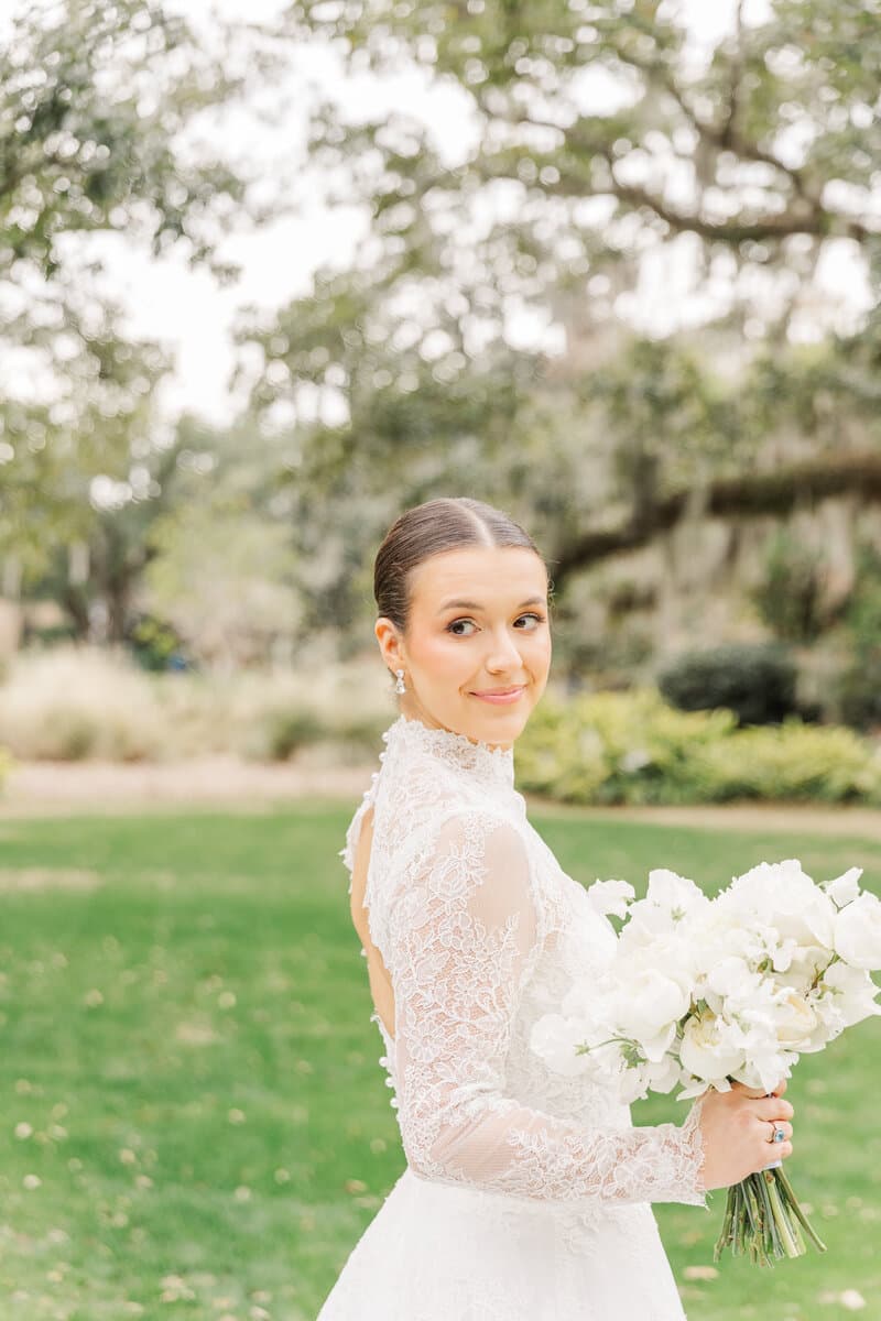 Bride holding her bouquet beneath a moss-draped oak