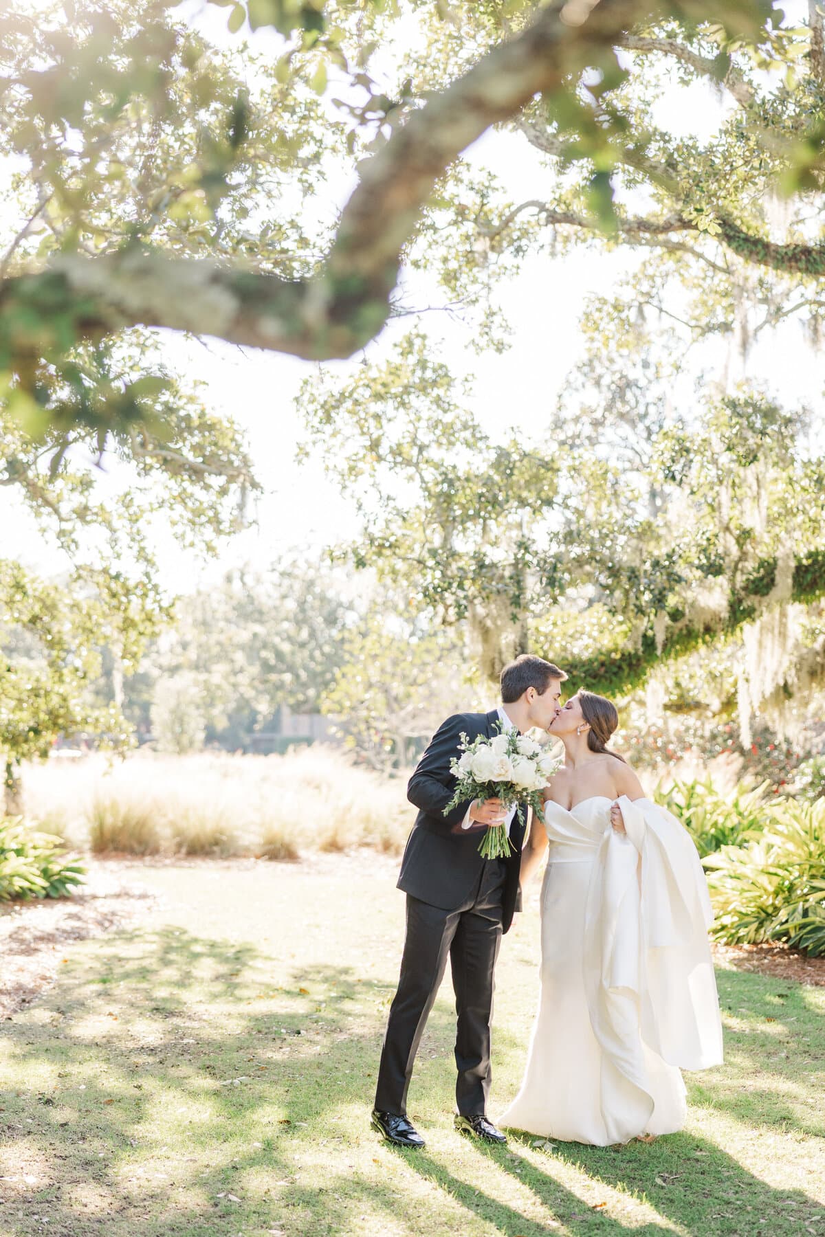 Bride and groom beneath a sunlit oak tree