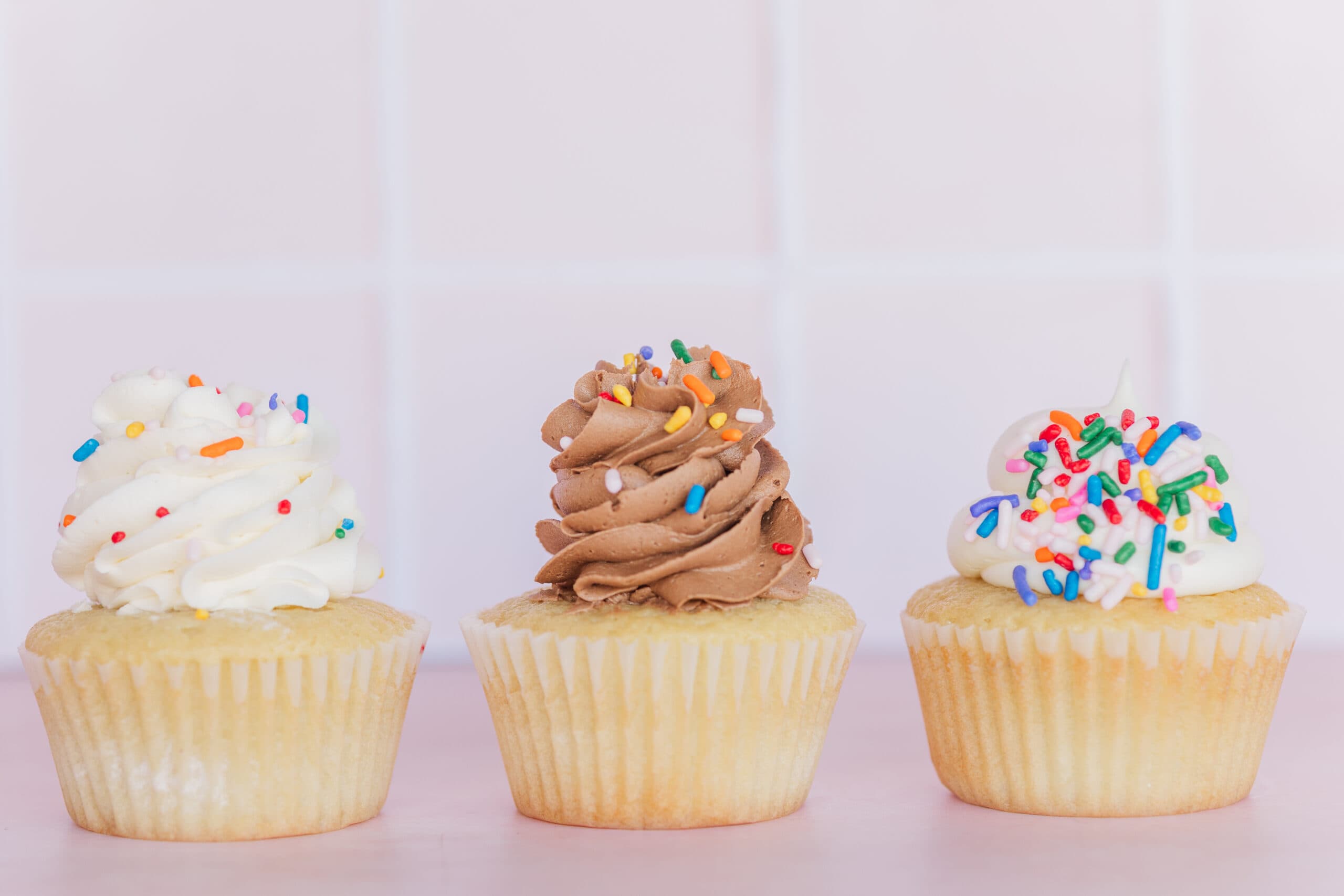 Three cupcakes from C Cups Cupcakery in Daphne, Alabama, topped with colorful frosting and sprinkles — part of a small business brand photography session by Jennie Tewell Photography.