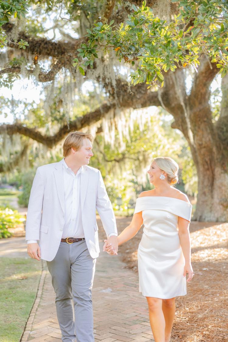 Romantic couple Audrey and Lyon, bathed in soft sunlight, share a loving moment beneath the mossy oak trees at the picturesque Grand Hotel in Fairhope.