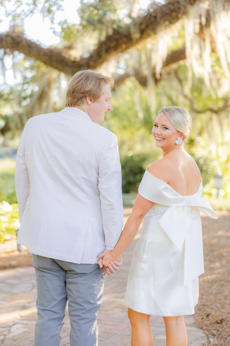 Romantic couple Audrey and Lyon, bathed in soft sunlight, share a loving moment beneath the mossy oak trees at the picturesque Grand Hotel in Fairhope.