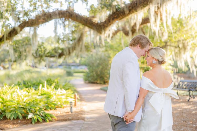Romantic couple Audrey and Lyon, bathed in soft sunlight, share a loving moment beneath the mossy oak trees at the picturesque Grand Hotel in Fairhope.