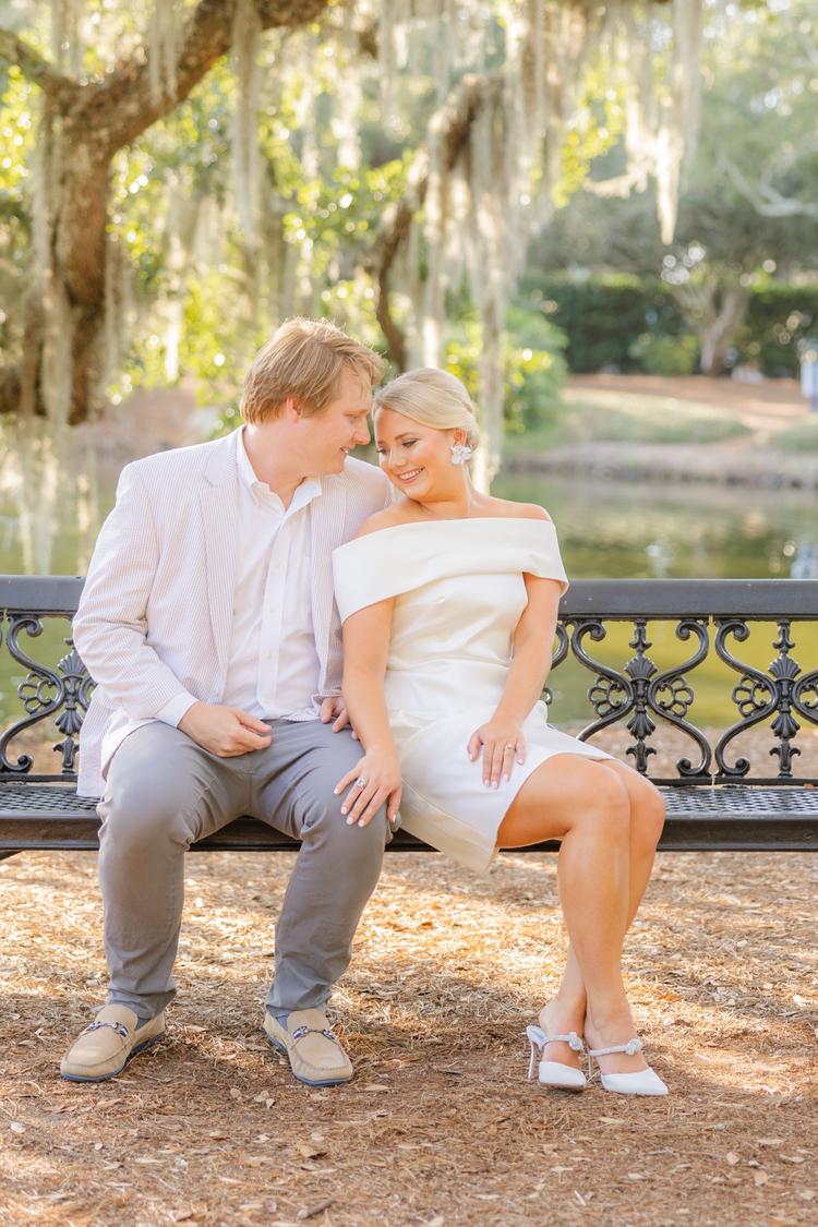 Romantic couple Audrey and Lyon, bathed in soft sunlight, share a loving moment beneath the mossy oak trees at the picturesque Grand Hotel in Fairhope.
