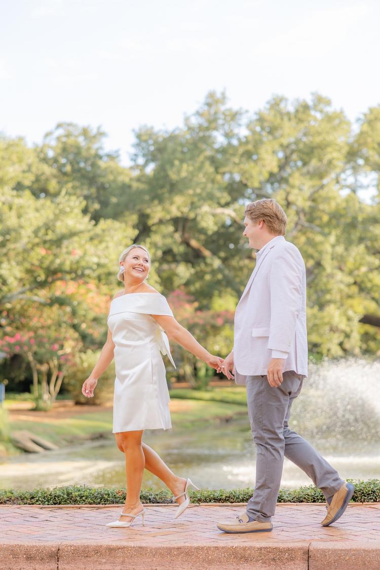 Romantic couple Audrey and Lyon, bathed in soft sunlight, share a loving moment beneath the mossy oak trees at the picturesque Grand Hotel in Fairhope.