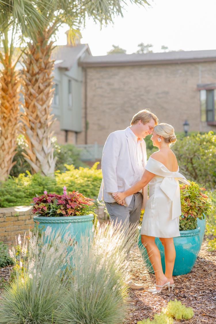 Romantic couple Audrey and Lyon, bathed in soft sunlight, share a loving moment beneath the mossy oak trees at the picturesque Grand Hotel in Fairhope.