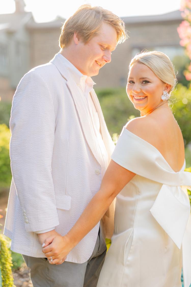 Romantic couple Audrey and Lyon, bathed in soft sunlight, share a loving moment beneath the mossy oak trees at the picturesque Grand Hotel in Fairhope.