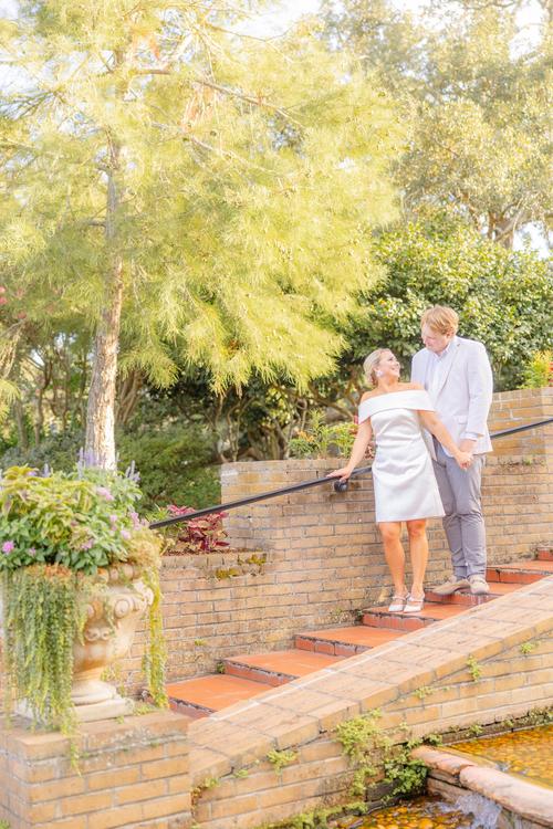 Romantic couple Audrey and Lyon, bathed in soft sunlight, share a loving moment beneath the mossy oak trees at the picturesque Grand Hotel in Fairhope.