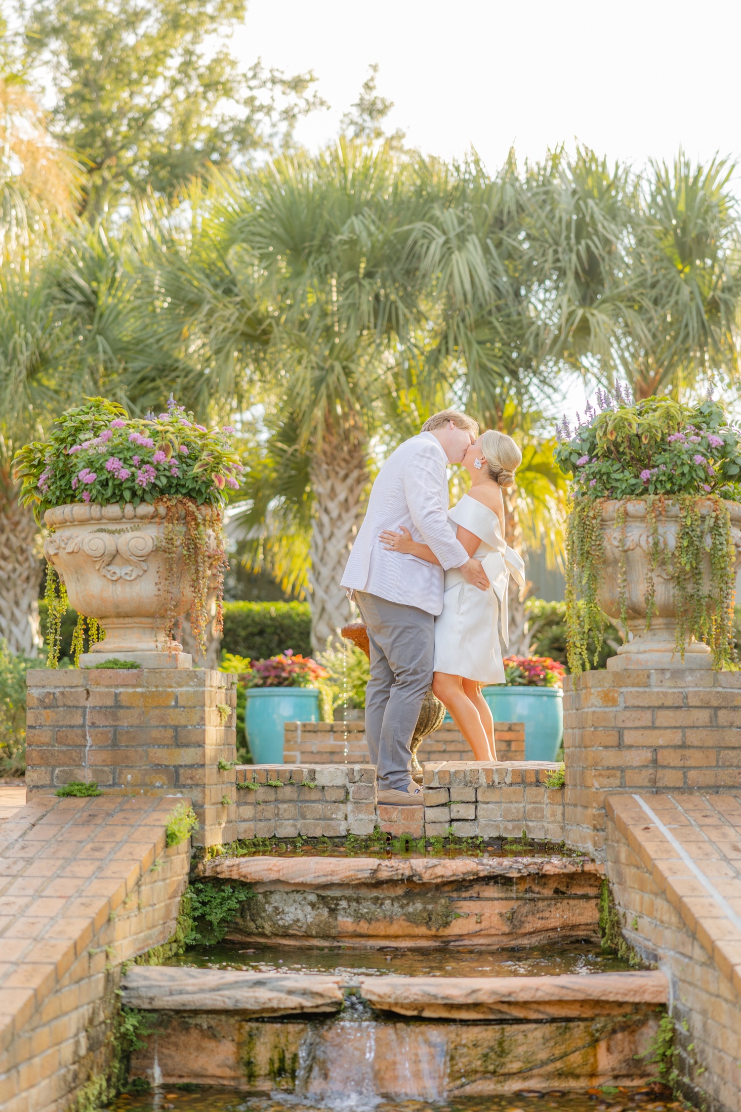 Romantic couple Audrey and Lyon, bathed in soft sunlight, share a loving moment beneath the mossy oak trees at the picturesque Grand Hotel in Fairhope.