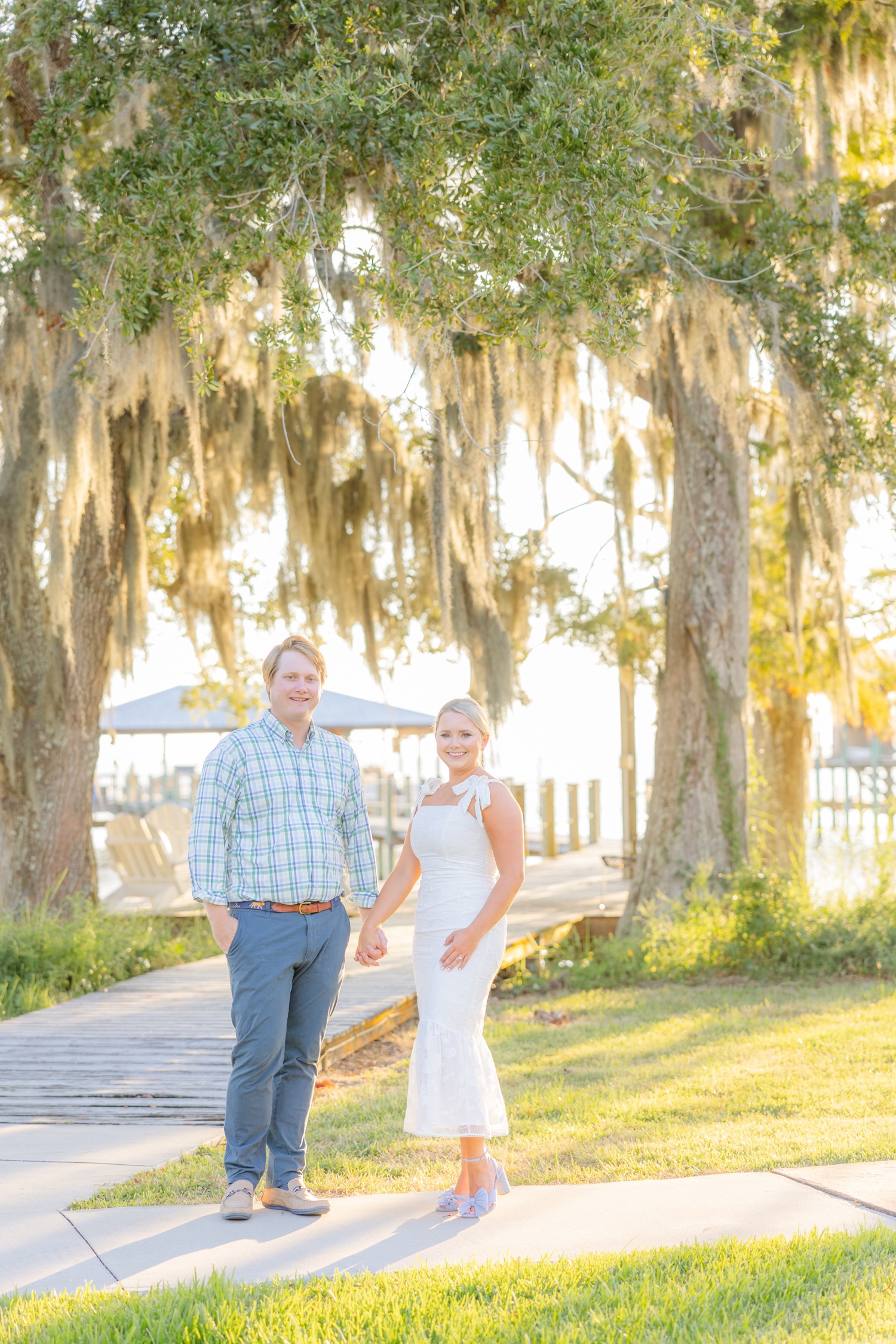 Romantic couple Audrey and Lyon, bathed in soft sunlight, share a loving moment beneath the mossy oak trees at the picturesque Grand Hotel in Fairhope.
