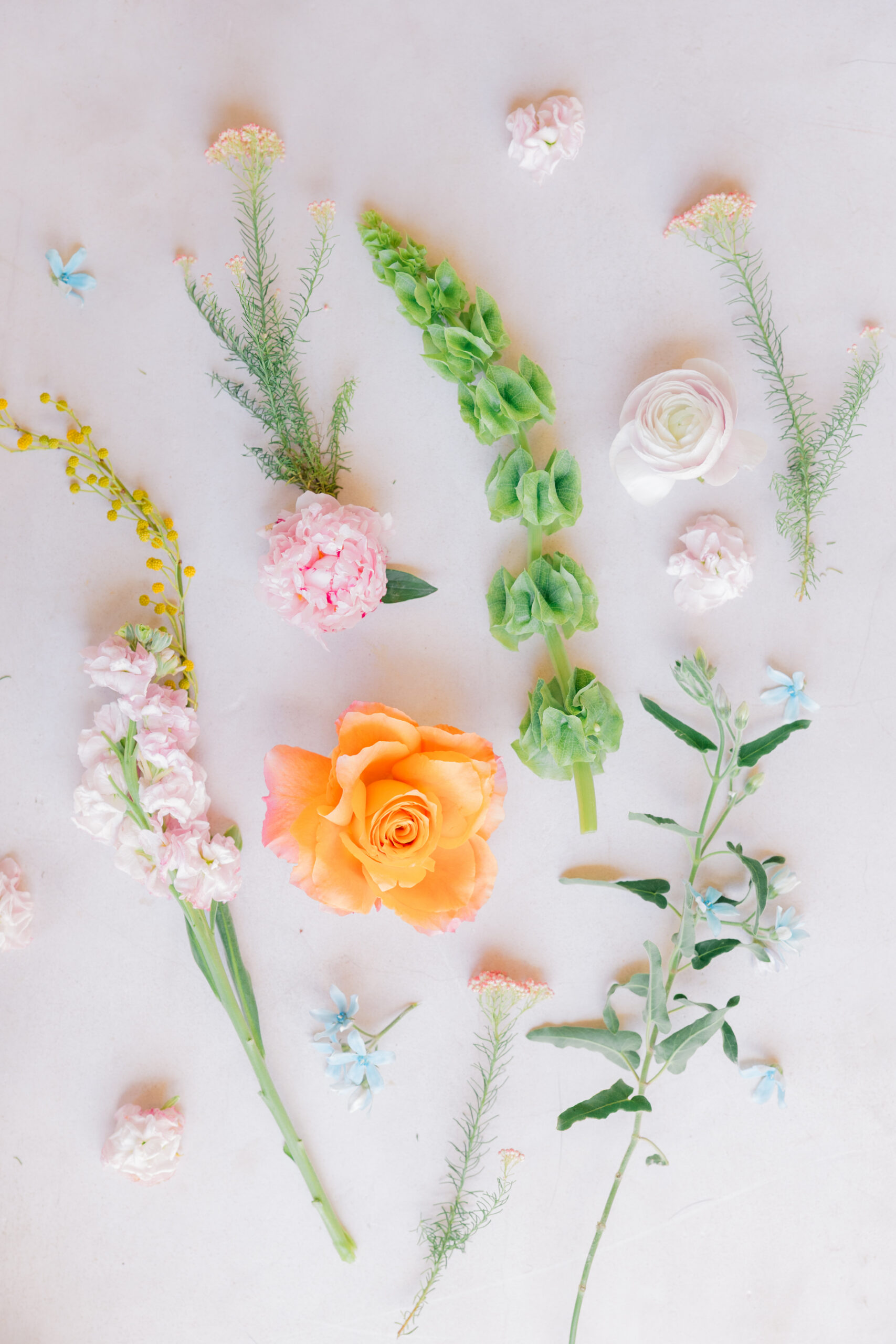 Wedding floral flat lay with peach rose, greenery, and pastel blooms in Fairhope, AL